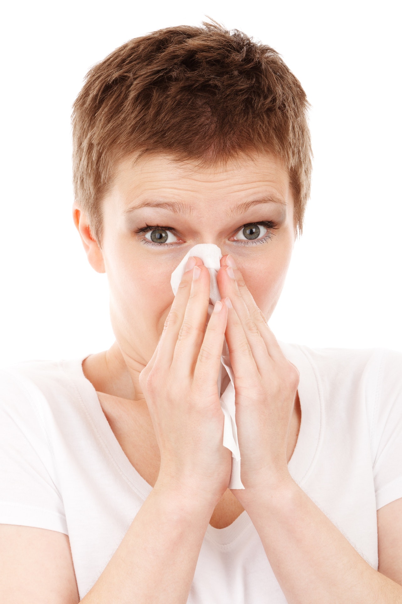 Woman with short hair holding a tissue about to blow her nose