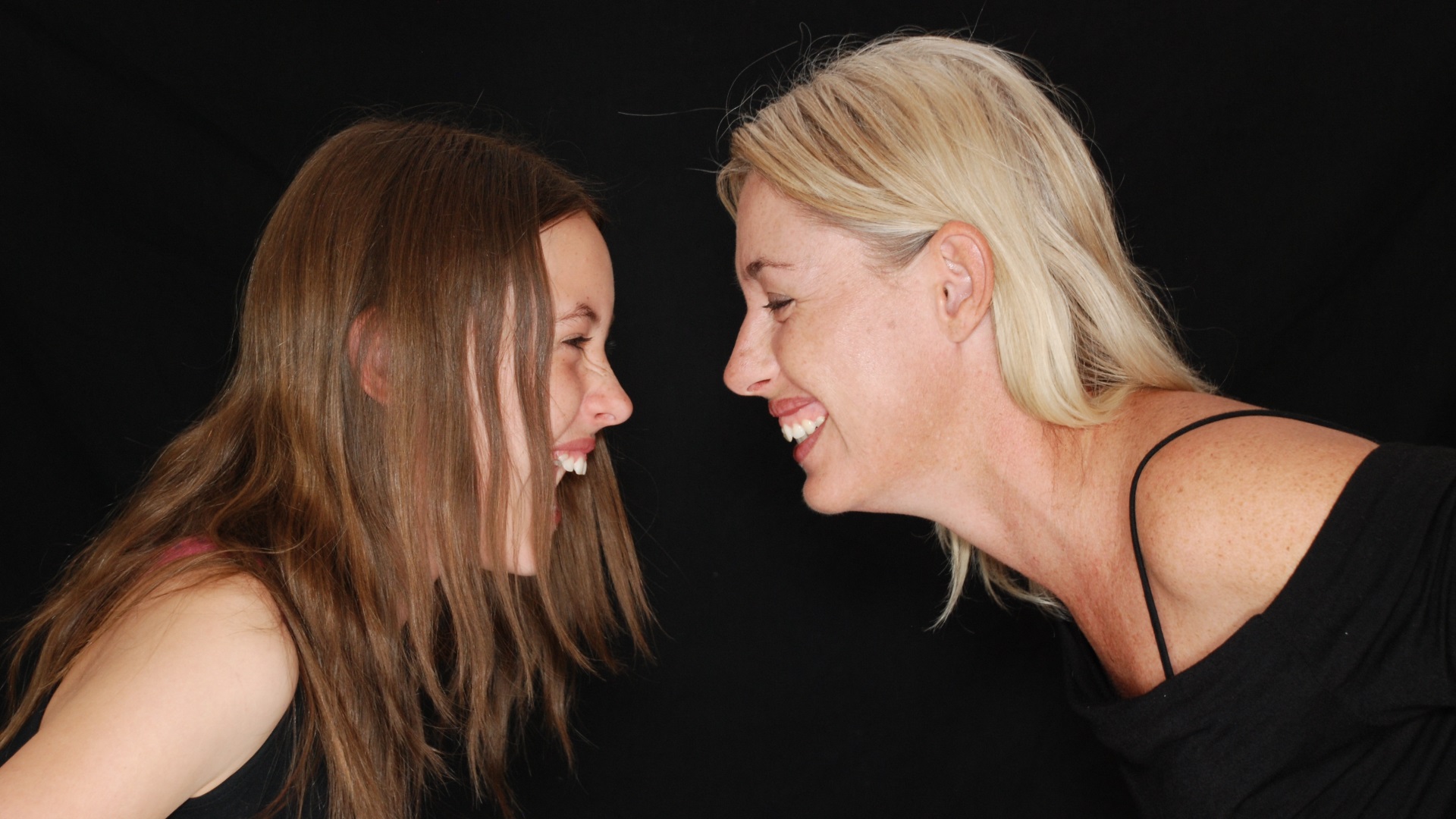 Two woman smiling and looking at each other leant over